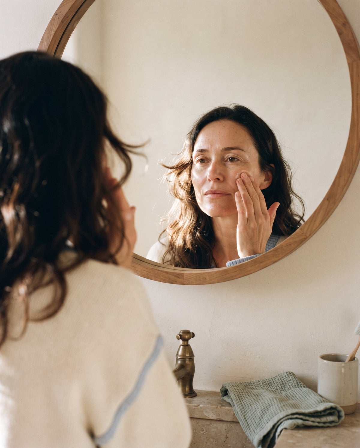Person with calm, settled skin pausing mid-way through an evening skincare routine