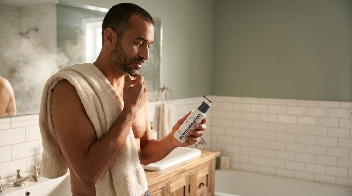 Man holding a gentle cleanser in a warm bathroom on a winter morning, preparing for his skincare routine