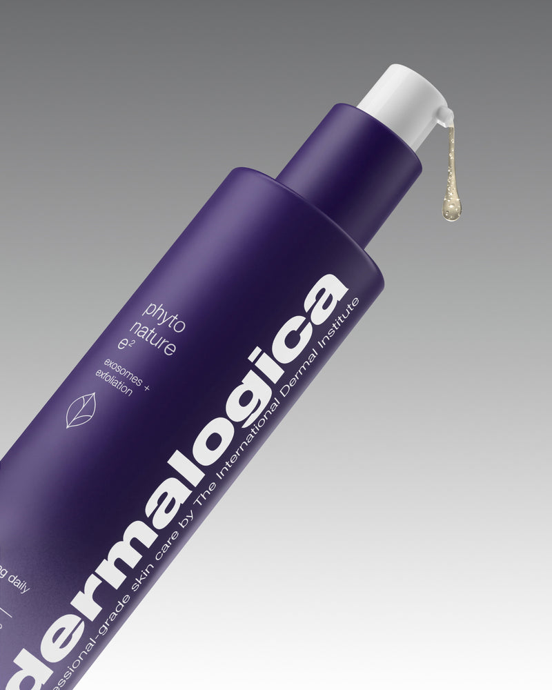 Purple Dermalogica Phyto Nature e² bottle angled on a grey gradient background, with a drop of serum dispensing from the pump. Text on bottle reads “exosomes + exfoliation”.