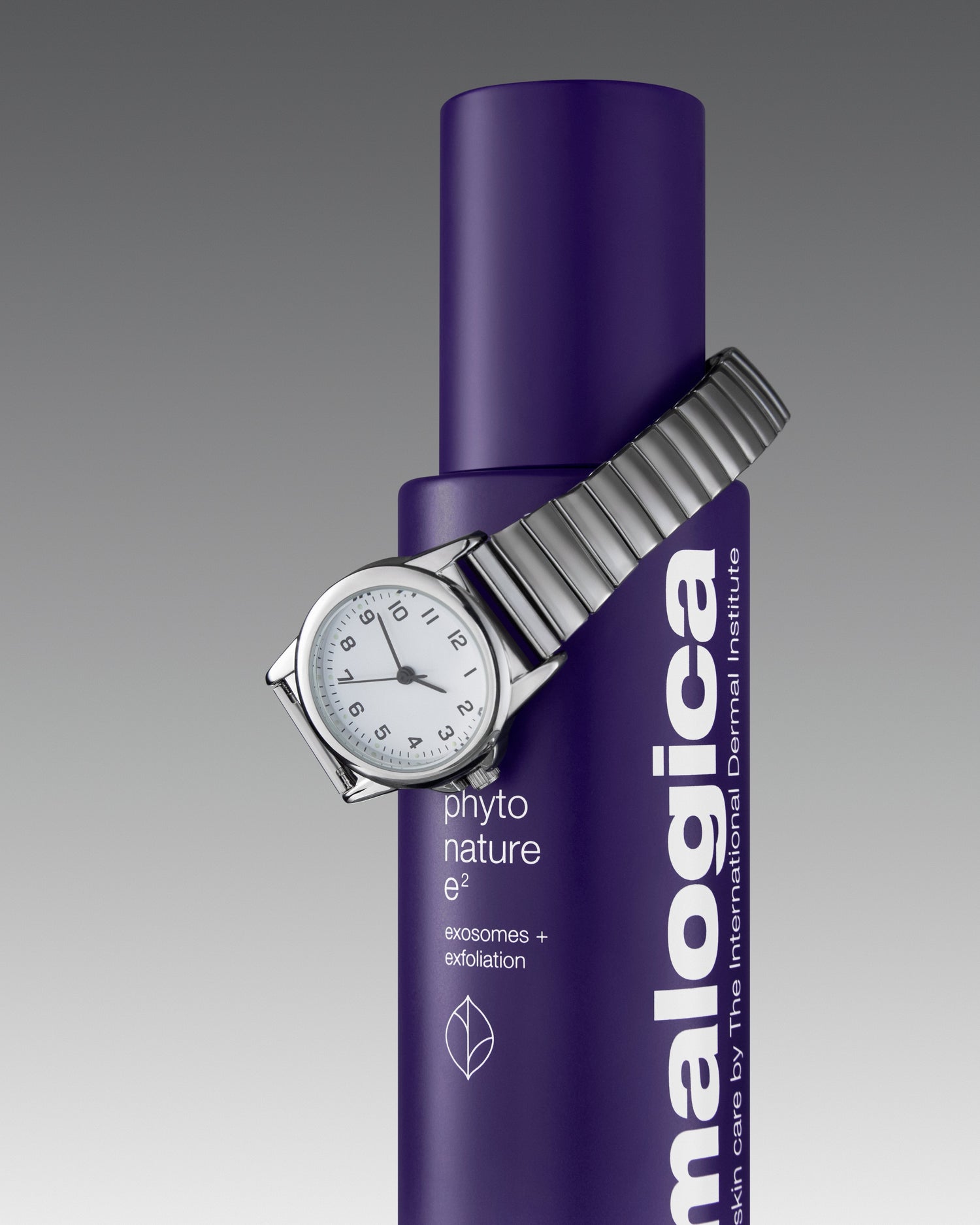 Silver wristwatch wrapped around a purple Dermalogica Phyto Nature e² bottle, featuring product text that highlights "exosomes + exfoliation" on a grey gradient background.